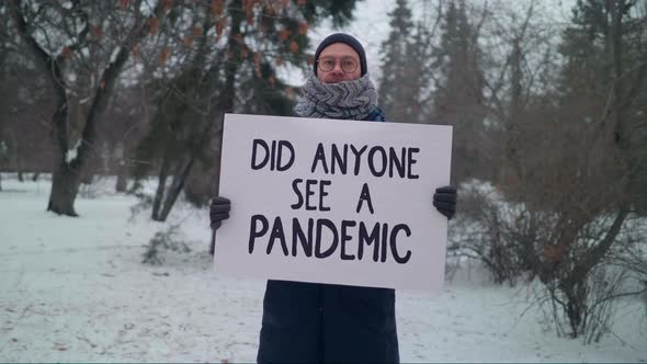 A male protester in a winter park is Holding a Sign Did Anyone See a Pandemic