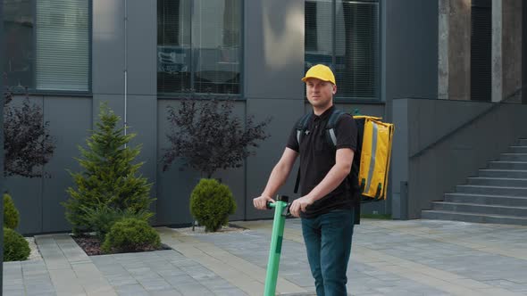 Handsome Young Caucasian Delivery Man Riding on a EScooter Bringing the Order