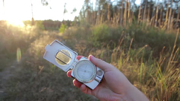 A man holds a compass in his hand and looks for direction