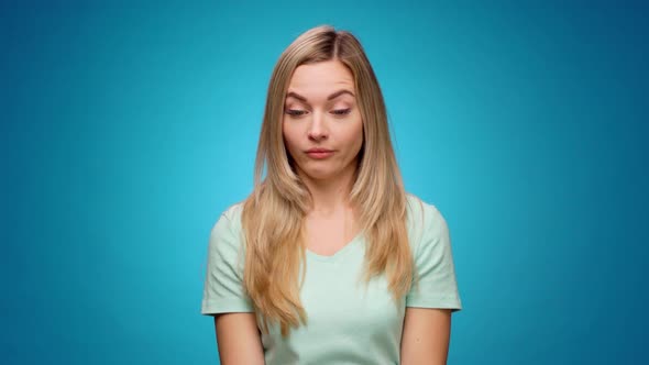 Beautiful Young Woman Grimaces As If Looking at Something Unpleasant Against Blue Background