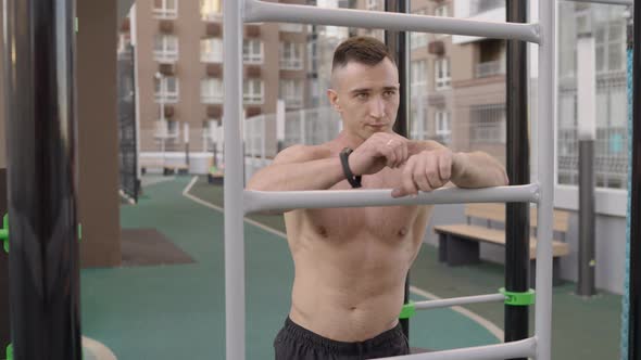 Handsome Young Caucasian Male with Naked Muscular Torso Posing at Outdoor Sports Ground Outdoor Gym