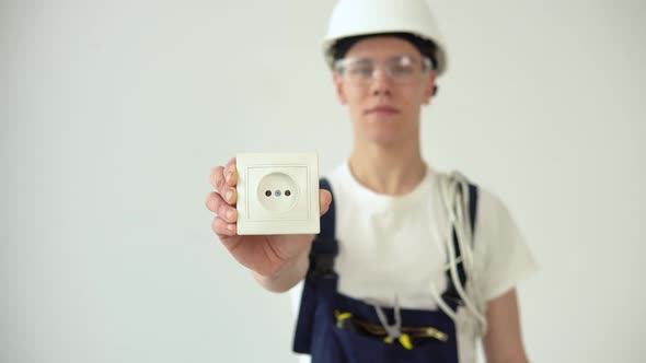 The Electrician Holds the Sockets in His Hand and Looks Straight Ahead