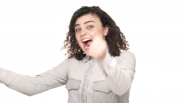 Portrait of Delighted Female Gamer with Dark Curly Hair Screaming and Clenching Fists When Winning