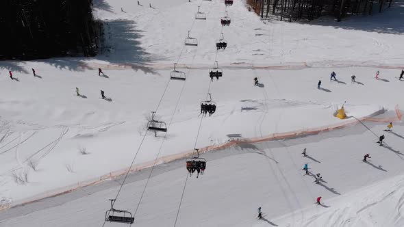 Aerial View of Ski Slopes with Skiers Go Down Under Ski Lifts on Ski Resort