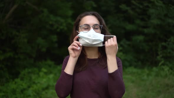 A Young Woman with Glasses Takes Off the Medical Mask and Throws It Away