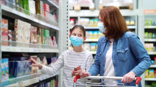 Mother and Daughter in Masks in Sweets Department in Supermarket