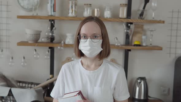 Portrait of a Young Woman in Mask and Tshirt Books in Her Hands