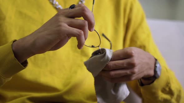 An African American Man's Hands Clean the Lenses of His Glasses with a Microfiber