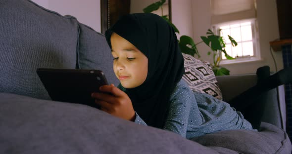 Girl in hijab using digital tablet in living room 4k