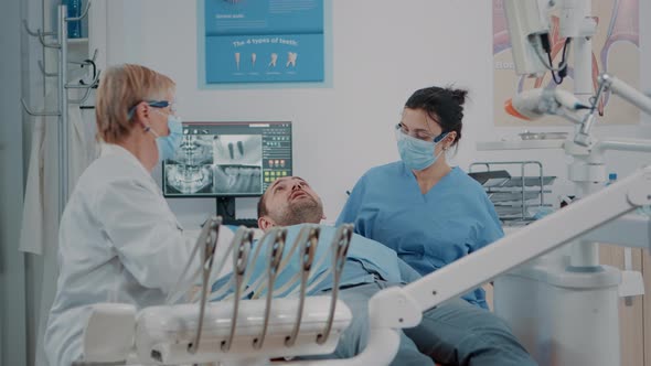 Stomatologist and Nurse Finishing Oral Care Procedure with Patient