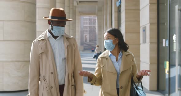 Young African Colleagues in Medical Mask Walking Outside Modern Building