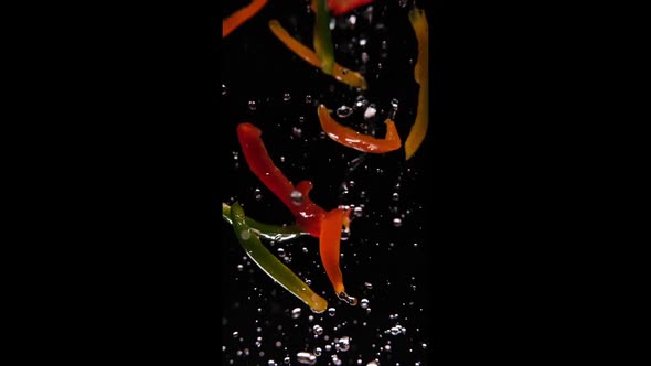 Bell peppers flying in the air splashing with water in slowmotion