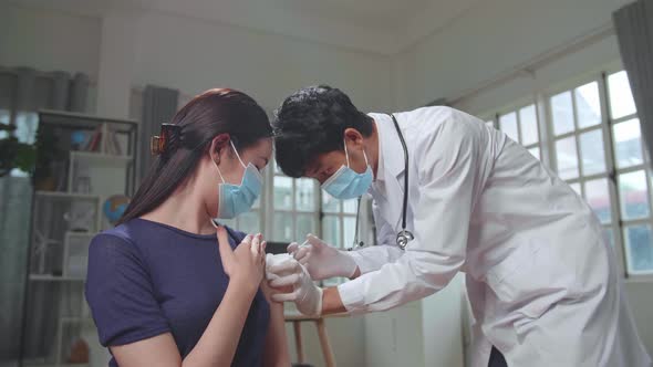 Doctor In Safety Gloves And Protective Mask Is Making A Vaccine Injection To A Female Patient