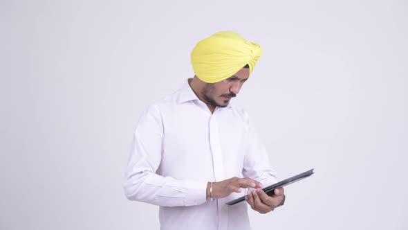 Stressed Bearded Indian Sikh Businessman Using Digital Tablet and Getting Bad News