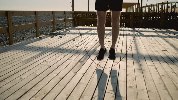 Man Is Training Outdoors Using Jumping Rope Closeup of Legs