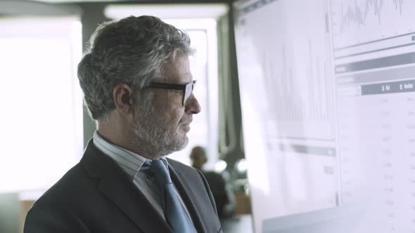 Experienced Greyhaired CEO Checking Data on Big Screen