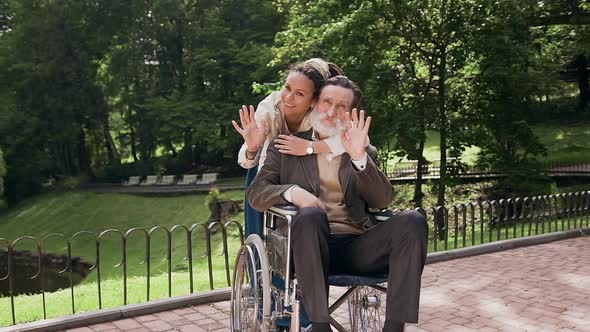 Man in Wheelchair and Charming Smiling Modern Girl with Dreadlocks Posing on Camera