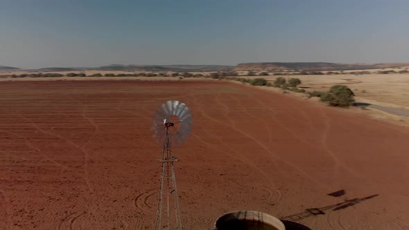 Aerial close up Rotating shot of a working windpump in a dry field