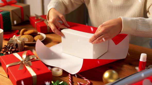 Woman Wrapping Christmas Gift Into Paper at Home