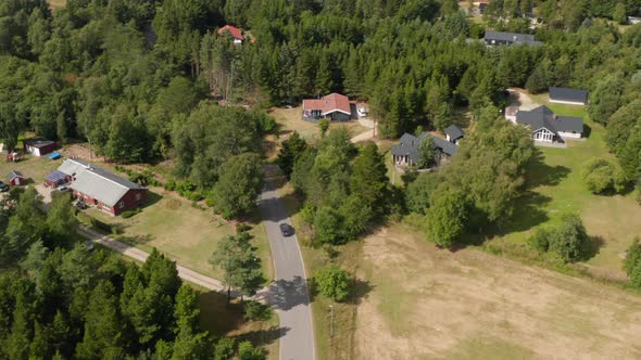 Road Winding Between Trees and Low Houses in Village