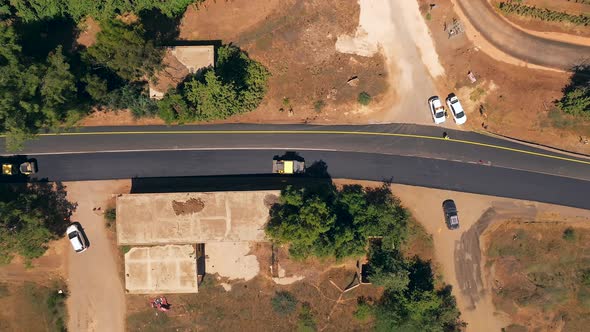 Road roller pressing fresh put Asphalt on a new road, Aerial follow footage.