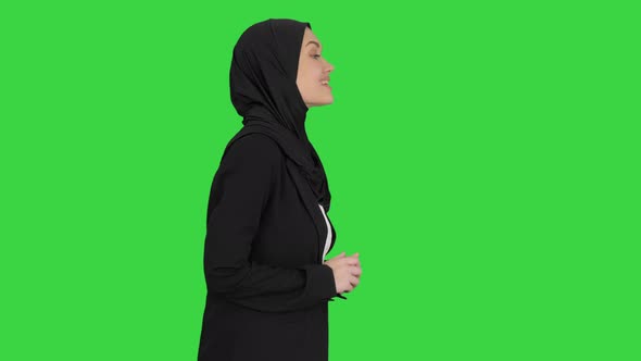 Smiling Arab Woman Wearing Hijab Talking About Business While Walking and Gesturing on a Green