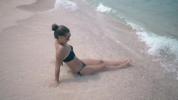 Girl in Black Bikini Enjoys Waves and Woman Walks in Water