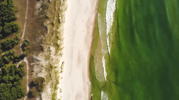 AERIAL: Flying extremely high over the sunny sandy beach