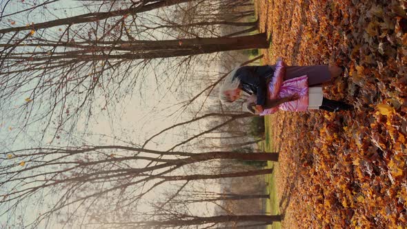 Mother and daughter hugging in autumn forest park. Females persons spend time together. Vertical