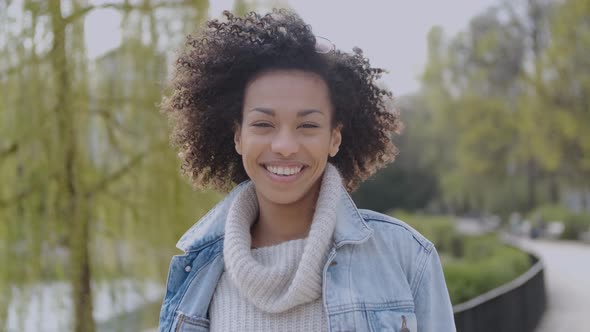 Happy and Smiling Mixed Race Girl with Afro Haircut Walking at the Park