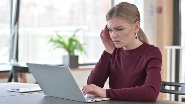 Young Woman with Headache Using Laptop in Office 