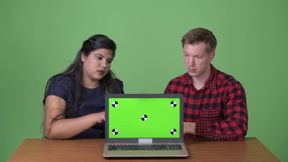 Young Multi-ethnic Business Couple Together Against Green Background