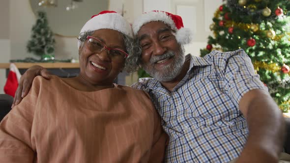 Animation of happy african american senior couple having video call at christmas time