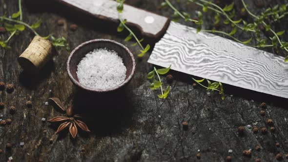 Animation of damascus knife with fresh herbs and spices on wooden table.
