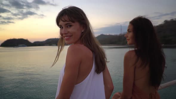Two Lovely Brunette Models are Posing with Their Backs to the Camera with Sunset Sky in the