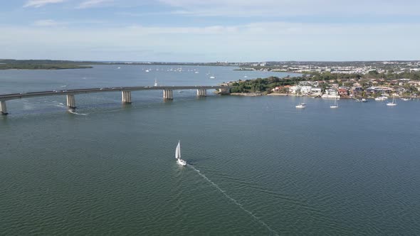 Aerial view around a sailboat, sailing in front of the bridge, summer morning in Taren Point, Sydney