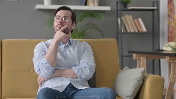 Young Man Thinking While Sitting on Sofa