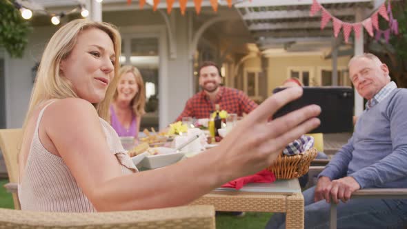 Three generation family taking a selfie while enjoying lunch outdoors