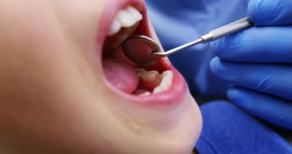 Dentist examining a young patient with tools