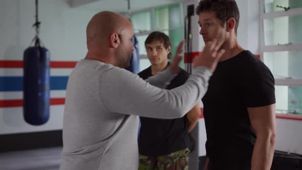 Caucasian coach giving advice to two athletes in boxing gym