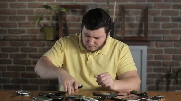 man in office is looking for right phone in large pile of old outdated phones.