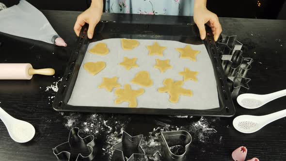 Cookies in different shapes of raw dough on baking sheet
