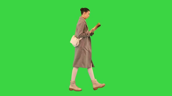 Young Woman Walking and Reading a Book on a Green Screen Chroma Key