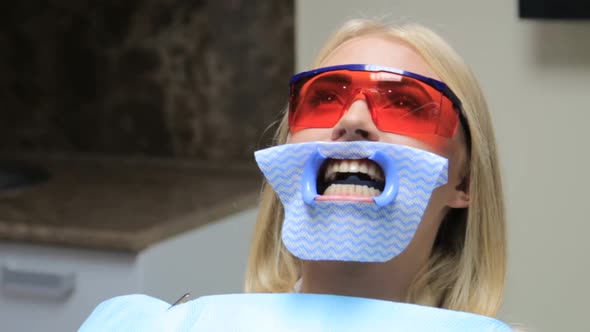 Dentist treating teeth to woman patient in clinic.