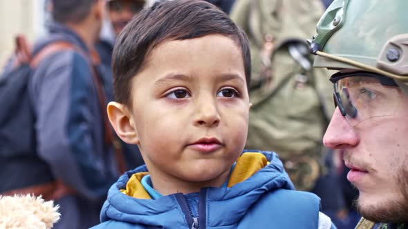 Little Refugee Boy Talking with Soldier