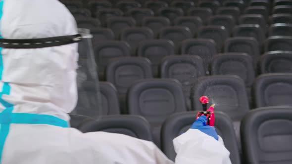 Worker in Protective Clothes Cleaning Cinema Hall