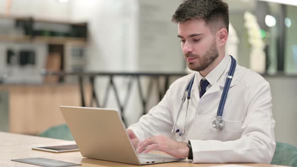 Focused Young Doctor Working on Laptop in Office 
