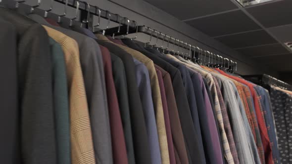 Row of Men Suit Jackets on Hangers in Different Colors. Men's Jackets on Hangers in the Men's Store
