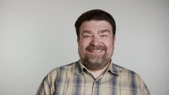 Unshaven bearded aged man in gray blue shirt isolated over gray background