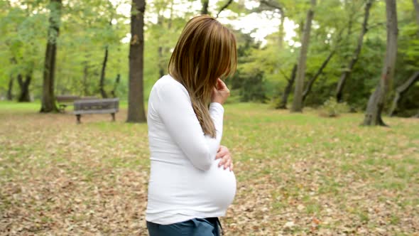 Young Pretty Pregnant Woman Walk Around and Think About Something in Park